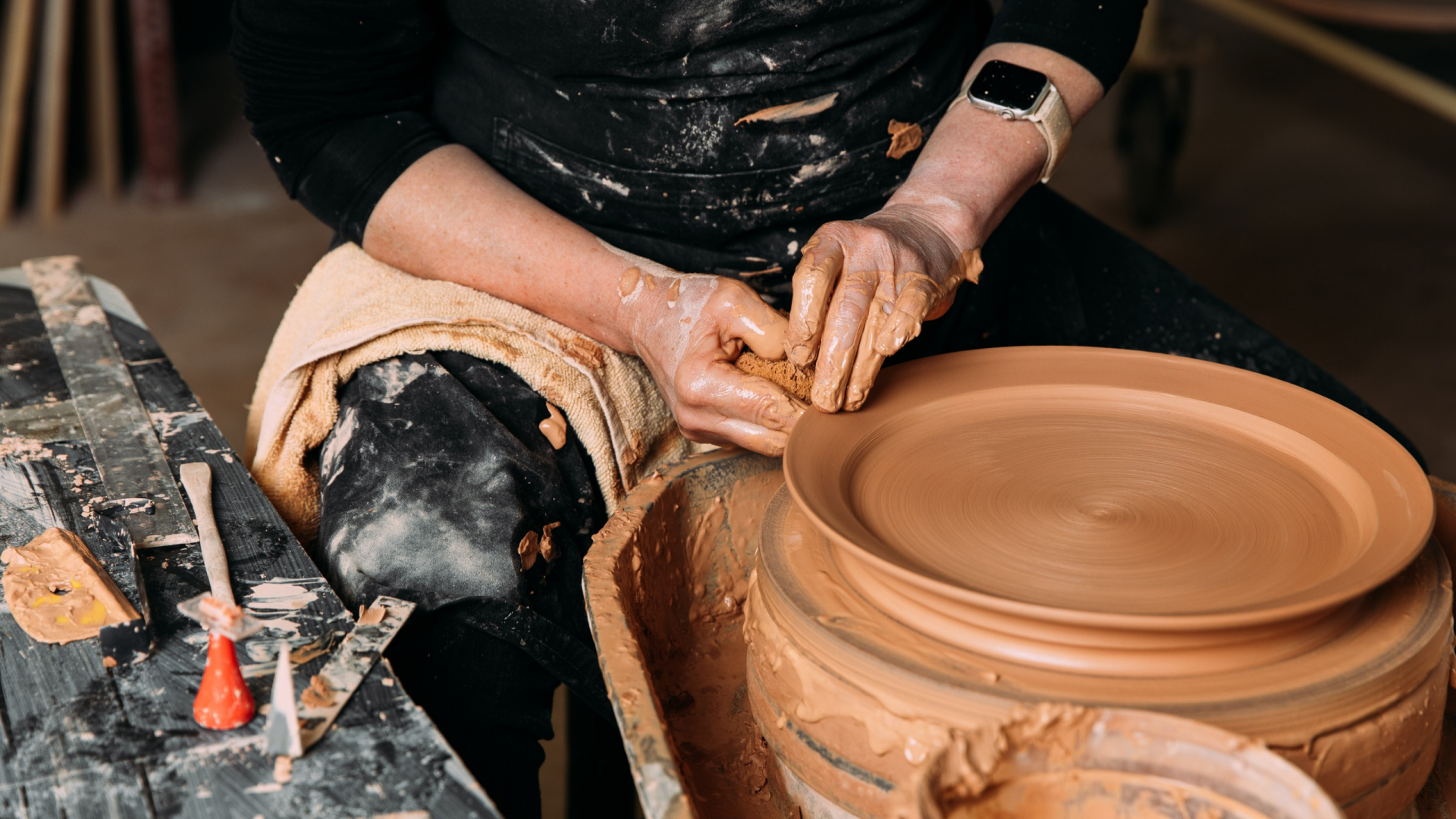 Photo of a JamFactory ceramic artist throwing a clay plate on the wheel