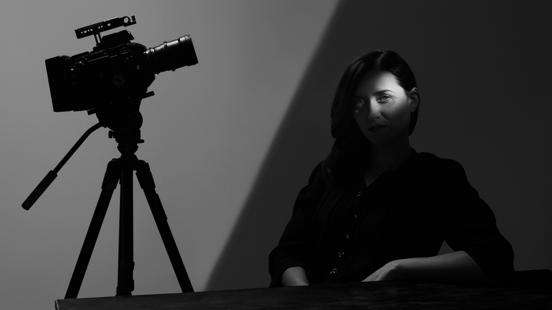photo of female cinematographer with her camera equipment in half shadow