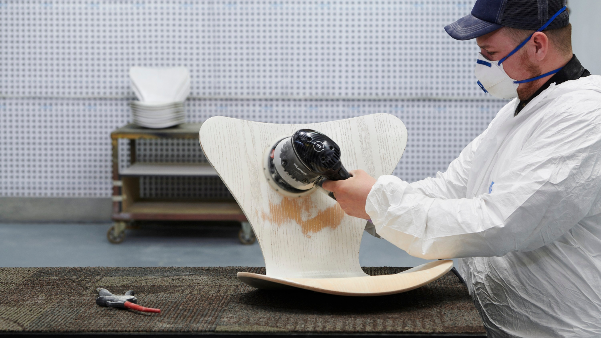 Wood worker sanding the paint off a used Fritz Hansen Series 7 Chair