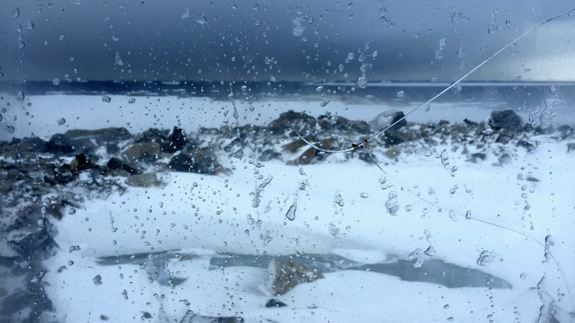 View of ice and rocks through a window spattered with rain drops