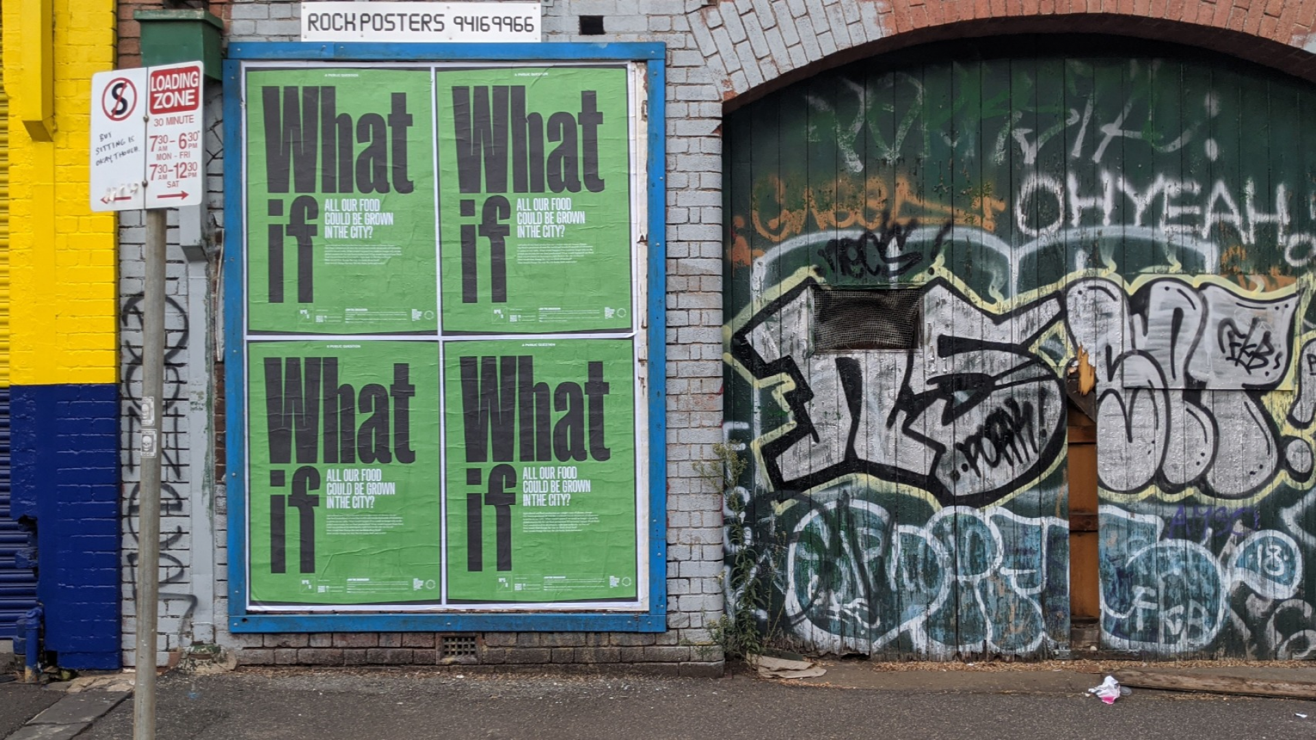 Four green posters are arranged in a grid on a heavily graffiti'd wall. The posters say 